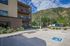 Contemporary apartment building with balconies set against a stunning mountain backdrop, featuring accessible parking spaces.