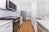 Modern kitchen with sleek stainless steel appliances, pristine white cabinetry, and elegant hardwood flooring.