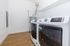 Modern utility room with sleek washer and dryer, efficient water heater, and elegant wood flooring.