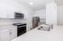 Modern kitchen featuring sleek stainless steel appliances, stylish white cabinetry, and a spacious quartz countertop with dual sinks.