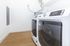Modern laundry room featuring sleek front-load washer and dryer on polished wood flooring.