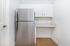 Sleek and modern kitchen corner featuring a stainless steel refrigerator, crisp white cabinets, and polished countertops, perfect for compact yet stylish living.