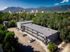 Breathtaking aerial view of a modern apartment building surrounded by lush greenery and stunning mountain scenery, conveniently located near the cityscape.
