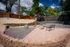 Charming backyard oasis with colorful gravel landscaping, stone accents, rustic seating, and lush greenery for a serene outdoor retreat.