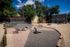 Charming outdoor space featuring a landscaped area with seating, picnic table, and natural rocks, perfect for relaxation under clear blue skies.