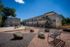 Charming apartment complex with modern, multi-level design, featuring accessible outdoor seating and inviting landscaping under a bright blue sky.