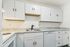 Modern kitchen featuring sleek white cabinetry, elegant marble countertops, and a stylish integrated sink and dishwasher.