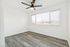 Bright, spacious room with sleek wood flooring, large window, and modern ceiling fan.
