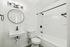 Elegant modern bathroom featuring a sleek white sink, round mirror, and contemporary lighting.