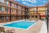 Vibrant apartment complex with a sparkling outdoor pool and inviting lounging area, perfect for relaxation under sunny skies.