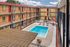 Charming apartment complex with a sparkling central pool, surrounded by sunny balconies with vibrant red doors.