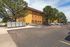 Charming apartment exterior with vibrant colors, ample parking, and lush trees for a peaceful setting.