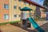Inviting apartment exterior with vibrant playground featuring a fun slide, ideal for family-friendly living.