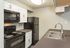 Modern kitchen with sleek black appliances, spacious countertops, and elegant white cabinetry.