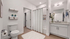 Elegant bathroom with modern fixtures, featuring a white vanity, chic shelving, and luxurious fluffy rug.
