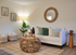 Chic and cozy living room with elegant decor, featuring a plush white sofa, stylish wicker coffee table, and vibrant green plants.