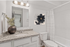 Elegant bathroom featuring a granite countertop, modern fixtures, and tasteful floral wall art, offering a serene and stylish space.