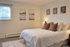 Elegant bedroom with a cozy queen-sized bed, adorned with plush pillows and ambient lighting, complemented by tasteful wall art and a serene window view.