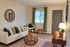 Cozy living room with a stylish white sofa, colorful throw pillows, a wicker coffee table, and warm decor, exuding a welcoming atmosphere.