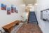 Inviting apartment hallway with cozy blue-carpeted staircase, vibrant landscape artwork, elegant mailboxes, and a stylish wooden bench.