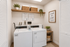 Modern and inviting laundry room featuring efficient washers and dryers, stylish shelving with decorative baskets, and lush greenery.