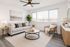 Bright and inviting living room with a cozy gray sofa, stylish round coffee table, and modern decor. Large windows allow natural light to flood the space, complemented by chic houseplants and elegant wall art.