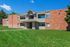 Charming apartment building with a classic brick exterior, lush green lawn, and inviting entrance, perfect for a cozy urban lifestyle.