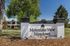 Inviting entrance to Mountain View Meadows, showcasing lush greenery and a welcoming community sign.