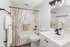 Modern bathroom with elegant fixtures, a pristine white vanity, and stylish lighting for a serene ambiance.