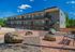 Modern three-story apartment building with stylish exterior, surrounded by a beautifully landscaped courtyard featuring benches and natural stone accents.