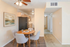 Charming dining area with modern gray chairs surrounding a wooden table, located near a sleek kitchen with light wood cabinets and a black refrigerator.