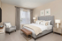 Elegant bedroom with a plush gray bed, sleek nightstand lamps, and stylish artwork, offering a serene and inviting atmosphere.
