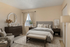 Elegant bedroom with plush bedding, contemporary decor, and natural light streaming through the window, creating a cozy and inviting atmosphere.