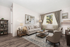 Elegant living room with modern decor, featuring a cozy beige sofa, stylish armchairs, and contemporary artwork. Bright natural light streams through large windows with luxurious curtains, creating an inviting ambiance.
