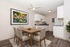 Charming dining area with elegant wooden table, stylish chairs, and a vibrant wall art, adjacent to a modern kitchen with sleek cabinets, set on warm wood flooring.