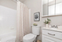 Elegant bathroom with modern fixtures, featuring a sleek vanity with mirror, fresh flowers, and calming art piece.