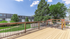 Spacious wooden deck with scenic views of lush greenery and modern apartment buildings under a bright blue sky.
