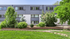 Modern apartment exterior with lush landscaping, vibrant green lawn, and stylish gray facade.