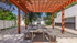 Charming outdoor space with a wooden pergola and rustic dining table, surrounded by lush greenery for a serene atmosphere.