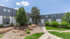 Beautiful modern apartment complex with lush landscaping, vibrant greenery, and a tranquil pathway under a clear blue sky.