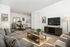 Elegant living and dining area with modern decor, cozy gray sofa, sleek wooden coffee table, and spacious dining set in a bright, open-concept apartment.