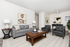 Modern living room with elegant gray sofa and armchairs, stylish wood coffee table, and contemporary artwork on white walls.