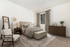 Elegant bedroom featuring a plush tufted bed, stylish modern chair, and sophisticated wooden furniture with soft natural lighting.