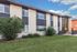 Modern apartment building with a sleek design, large windows, and well-maintained landscaping under a vibrant blue sky.