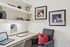 Chic home office corner with sleek desk, modern black chair, and vibrant red cushion, complemented by artistic wall decor and open shelving for a stylish workspace.