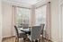 Elegant dining area with large windows, stylish patterned curtains, and a cozy round table with modern cushioned chairs.