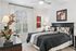 Charming bedroom with elegant decor, featuring a cozy bed, stylish artwork, and a large window allowing natural light.