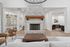 Inviting living space with elegant stone fireplace, cozy seating, and natural light through glass doors.