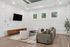 Elegant living room with modern decor, featuring a sleek wall-mounted TV, stylish furniture, and natural light from framed windows.