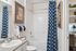 Charming bathroom with elegant blue geometric shower curtain, inviting bathtub, and stylish decor.